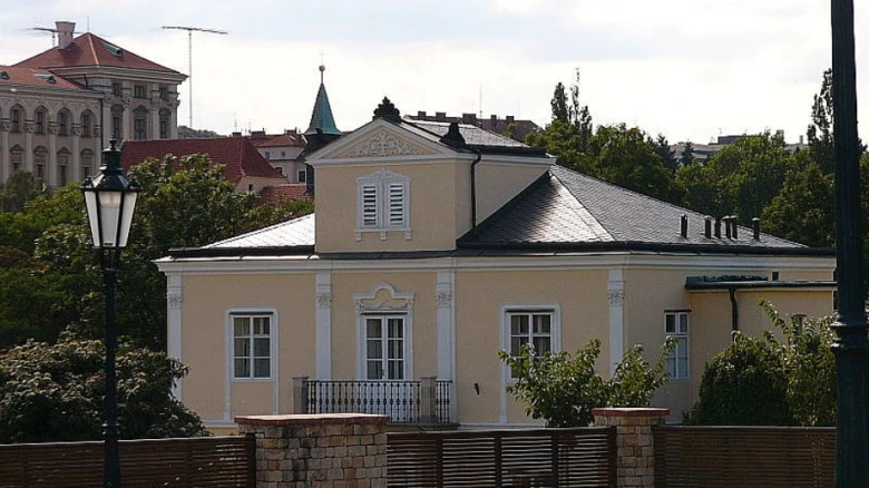 Fotografie Lumbeho vily s bílými okny na žluté fasádě.