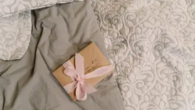 Malý dárek s růžovou stužkou na posteli.