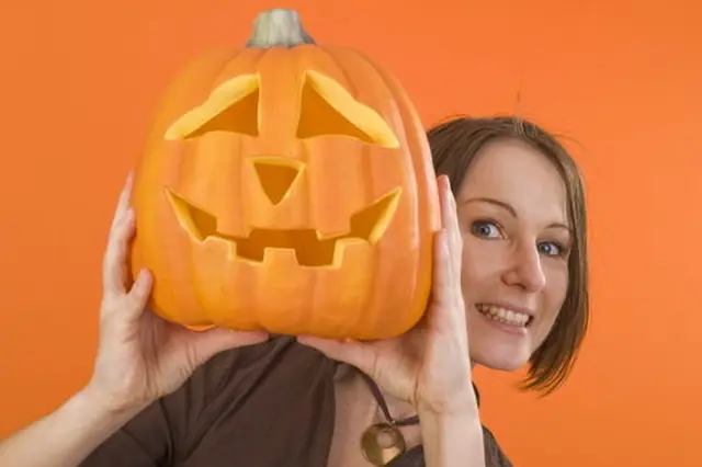 Carved pumpkin with woman holding it