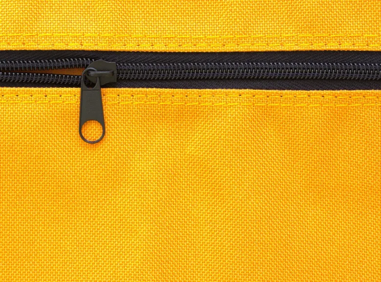 Žlutý zip na textilii s černým táhlem.