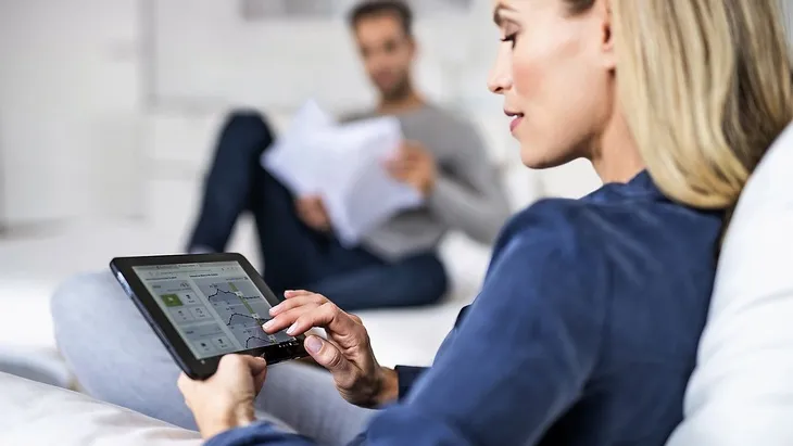 Žena v obýváku používá tablet pro zobrazení účtu za služby.