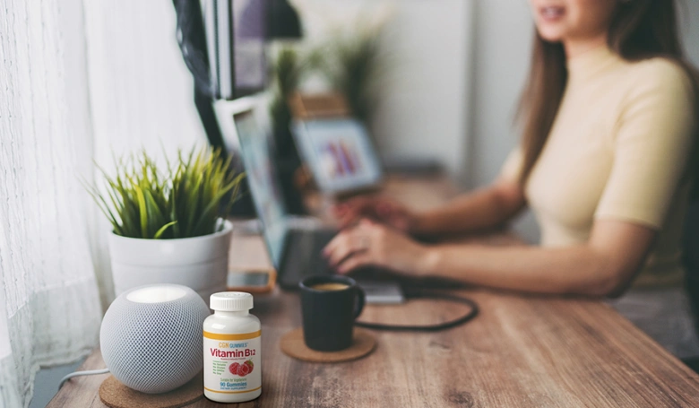 Žena pracuje s vitamínem B12, kávou a chytrým reproduktorem.