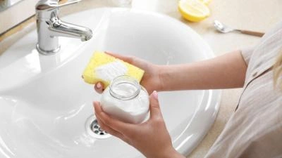 Člověk čistí umyvadlo sody octem citronem žlutou houbu