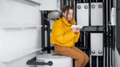 Žena sedí v technické místnosti s vodovodními instalacemi.