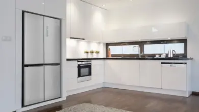 Moderní kuchyň s nerezovou chladničkou v bílém designu.