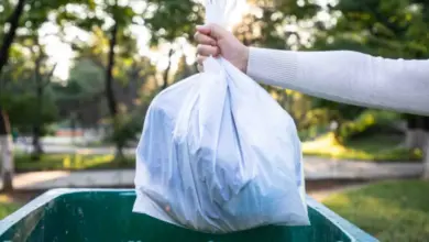 Hand holding trash bag over bin