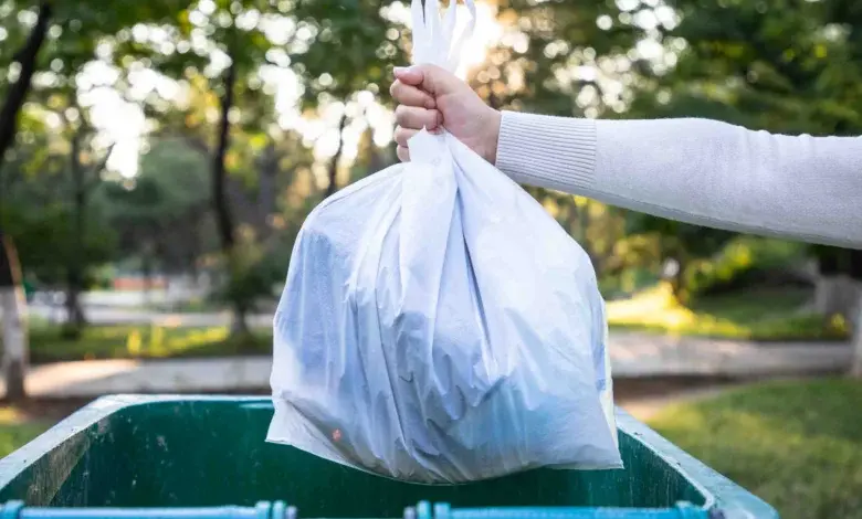 Hand holding trash bag over bin