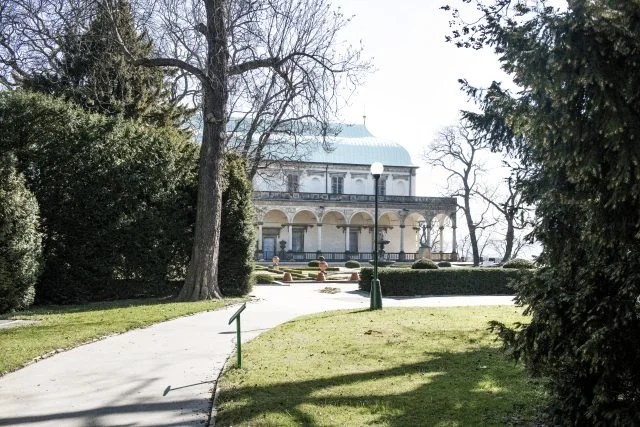 Fotografie Lumbeho vily s arkádou uprostřed parku.