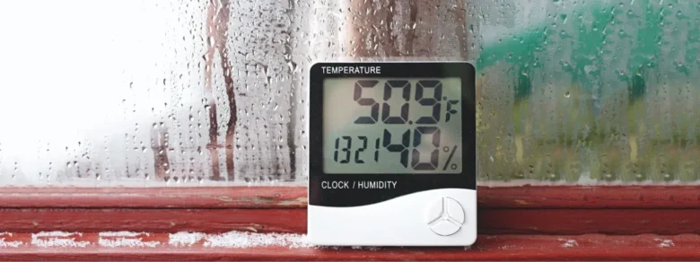 Digitální vlhkoměr ukazující relativní vlhkost vzduchu na parapetu.