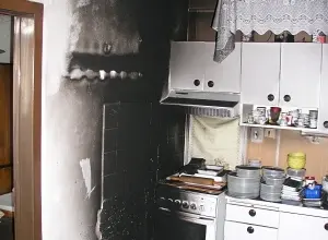 Zakouřená kuchyňská zeď po požáru vyžadující čištění.