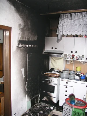 Zakouřená kuchyňská zeď po požáru vyžadující čištění.