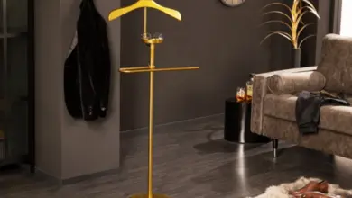 Zlatý němý sluha s kabátem na háčku v moderním interiéru.