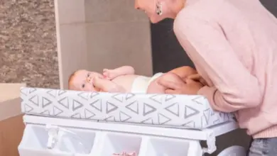 Matka mění miminko na přebalovacím pultu s úložným prostorem.