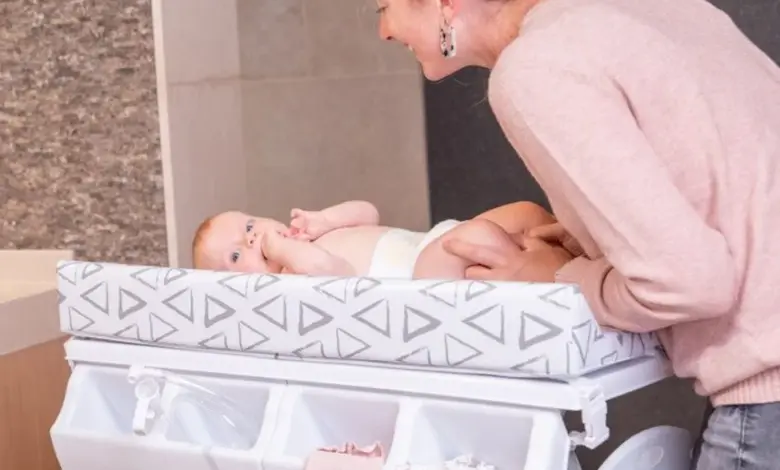 Matka mění miminko na přebalovacím pultu s úložným prostorem.