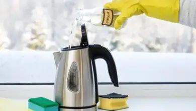 Ruka nalévá ocet do elektrického kotle pro čištění vodního kamene.