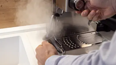Člověk čistí páru kávovaru vodou během odvápnění.