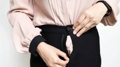 Žena opravuje rozbitý zip na černých kalhotách.