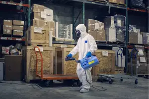 Osoba v ochranném obleku čistí sklad sprejem s čpavkem.