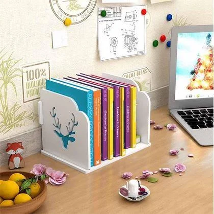 Bílá dekorativní knihovna s barevnými knihami na dřevěném stole vedle notebooku.