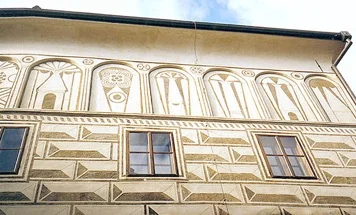 Detail sgrafita na fasádě budovy s geometrickými vzory.