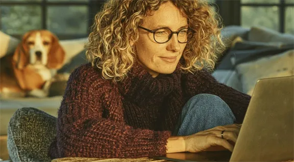 Žena s psíkem používá notebook v domově.