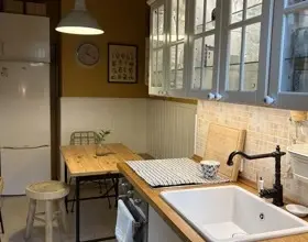 Interiér kuchyně s dřevěnými pracovními deskami a bílými skříněmi.