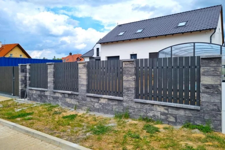 Moderní odolný plot ze šedých kamenů s tmavými lamelami.