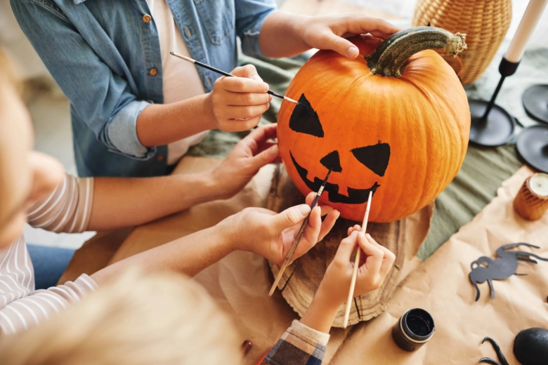 Lidé malují černé tváře na dýni před vyřezáváním pro halloween.
